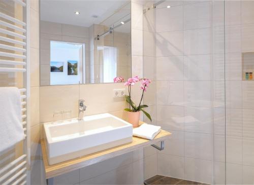 ein weißes Bad mit einem Waschbecken und einer Dusche in der Unterkunft Landgasthaus Hoffmann in Kruchten