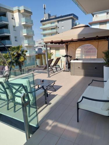 a patio with tables and chairs and an umbrella at Hotel Rossini 4S in Lignano Sabbiadoro