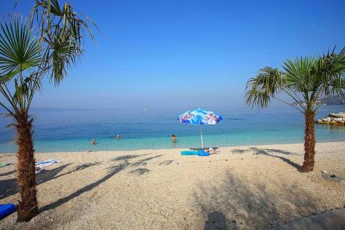 ein Strand mit Sonnenschirm und Menschen im Wasser in der Unterkunft Golden View Apartment in Duće