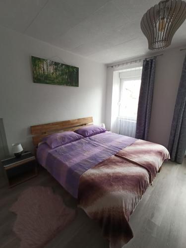 a bedroom with a large bed with purple sheets and a window at Apartment Nevela in Bovec