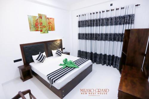 a bedroom with a bed with a green ribbon on it at Milano Grand in Dambulla