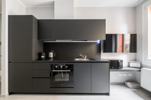 La cuisine est équipée de placards noirs et d'un four avec plaques de cuisson. dans l'établissement Marsala 19 Apartment by Wonderful Italy, à Bologne