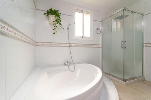 a white bathroom with a tub and a glass shower at Unio 36 in Ariany