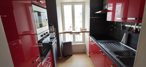 d'une cuisine avec des placards rouges, un évier et une fenêtre. dans l'établissement Au calme au coeur de Bayeux, à Bayeux