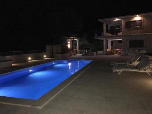a swimming pool at night in front of a house at Apartment Villa Morena in Čilipi