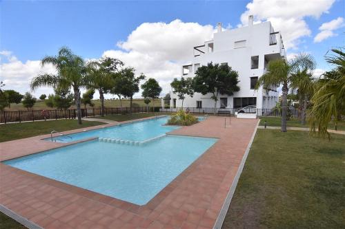 a swimming pool in front of a white building at Golf Course View Penthouse in El Romero