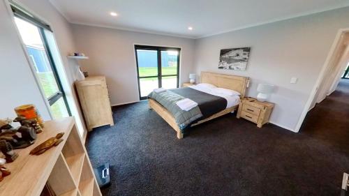 1 dormitorio con cama, escritorio y ventana en Full holiday home to yourself, up to 21 guests, en Atiamuri