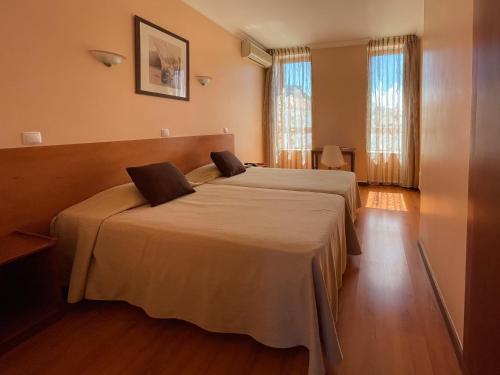 a hotel room with two beds and two windows at Imperio Hotel in Peso da Régua