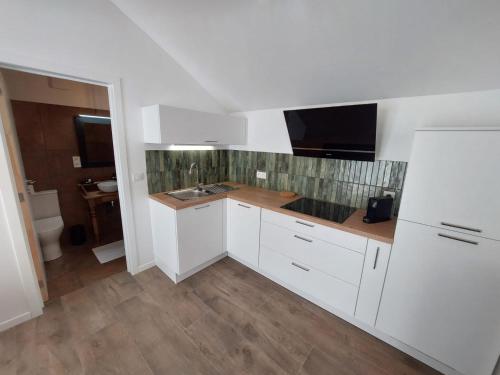 a kitchen with white cabinets and a sink at La Reid Champêtre in Theux