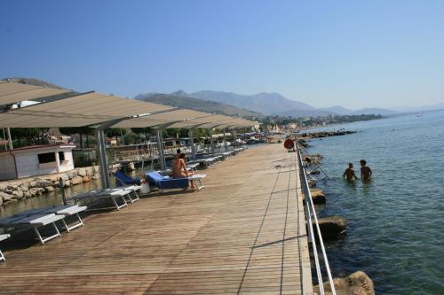 a wooden pier with people sitting in the water at Villa Irlanda Grand Hotel in Gaeta