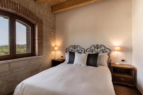 a bedroom with a white bed with two windows at Borgo Olivo in Pietrelcina