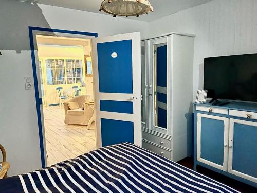 a bedroom with a blue and white bed and a television at Petite maison de vacance très proches de la mer in Saint Malo