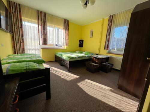 a room with two beds and a table and windows at Willa Ewa in Jantar