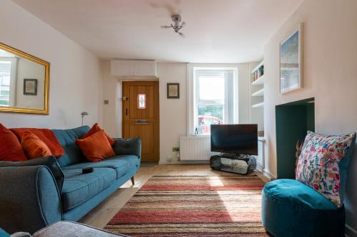 a living room with a blue couch and a tv at Hare Cottage in Abergavenny