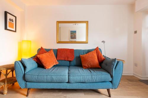 a blue couch with orange pillows in a living room at Hare Cottage in Abergavenny