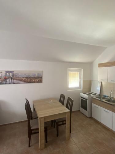 a kitchen with a wooden table and chairs in a room at Apartman Simona in Tivat