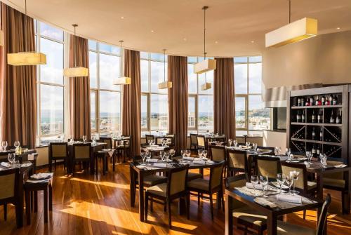 a restaurant with tables and chairs and large windows at TRYP by Wyndham Lisboa Caparica Mar in Costa da Caparica