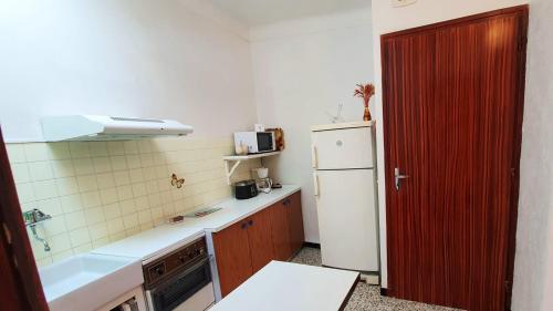 Il comprend une cuisine avec un réfrigérateur blanc et une porte rouge. dans l'établissement Studio 32 m² à Banyuls-sur-Mer avec terrasse agréable le jardin., à Banyuls-sur-Mer
