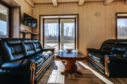 a living room with two leather couches and a coffee table at Kaimo turizmo sodyba „Šerno slėnis“ in Vėdariai