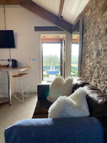 ein Wohnzimmer mit einem Sofa und einer Steinmauer in der Unterkunft Gardener's Cwtch, Llwynhelig Manor in Llandeilo