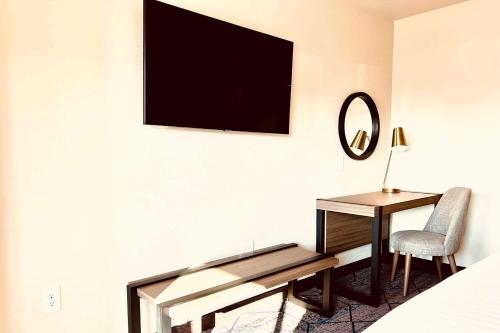 a hotel room with a desk and a television on a wall at Ramada by Wyndham Modesto Yosemite Area in Modesto