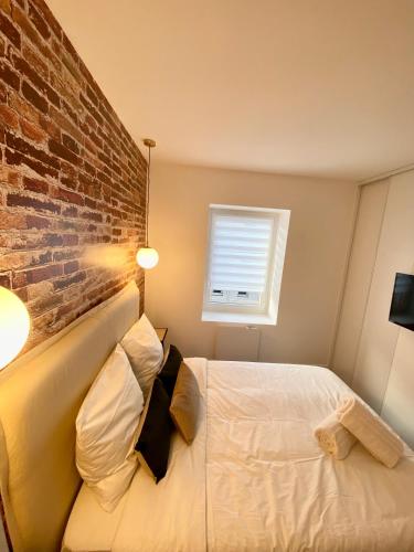 um quarto com uma cama e uma parede de tijolos em Le Grand Canyon em Saint-Étienne