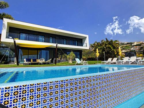 a house with a swimming pool in front of a building at Villa Skylark - by LovelyStay in Ponta do Sol