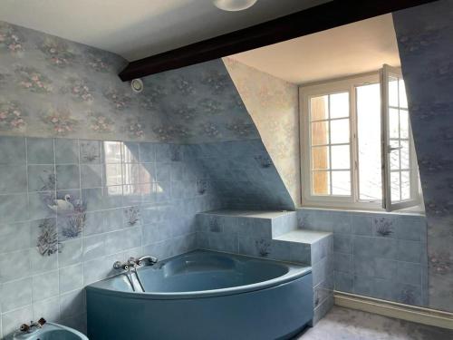 Una bañera azul en un baño con ventana. en Maison de campagne familiale sur la route des Châteaux, en Huisseau-sur-Mauves