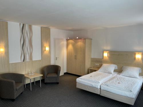a hotel room with a bed and two chairs at Hotel Mondial Comfort - Frankfurt City Centre in Frankfurt