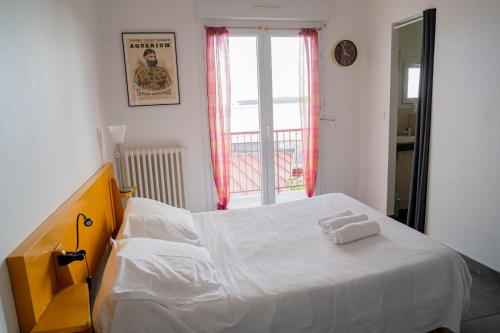 Schlafzimmer mit einem Bett mit weißer Bettwäsche und einem Fenster in der Unterkunft LE MOUTCHICO in Lacanau
