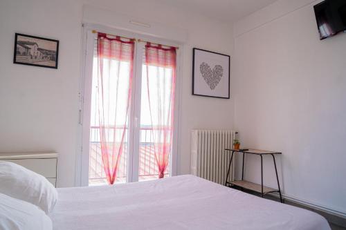 een witte slaapkamer met een bed en een raam bij LE MOUTCHICO in Lacanau