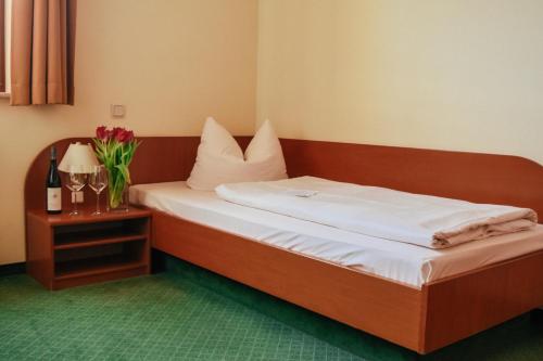 a bed in a room with a table with flowers on it at Landhotel Dresden in Dresden