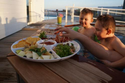 two boys sitting in the pool with a plate of food at Best Western Hotel Corallen in Oskarshamn