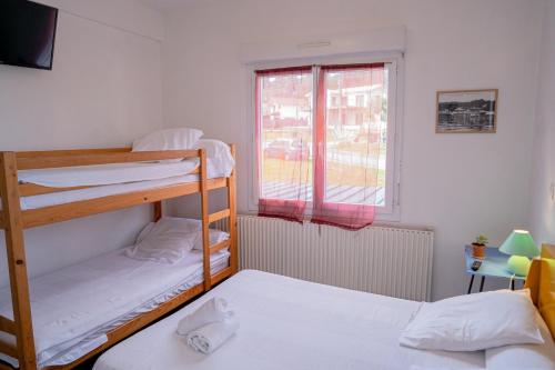 two bunk beds in a room with a window at LE MOUTCHICO in Lacanau