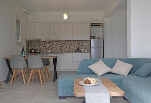 a living room with a blue couch and a kitchen at Olea Suite Syros - Φοίνικας, Σύρος, Κυκλάδες in Posidhonía