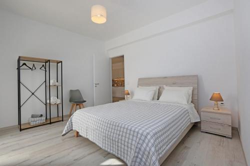 a white bedroom with a bed and a dresser at Olea Suite Syros - Φοίνικας, Σύρος, Κυκλάδες in Posidhonía
