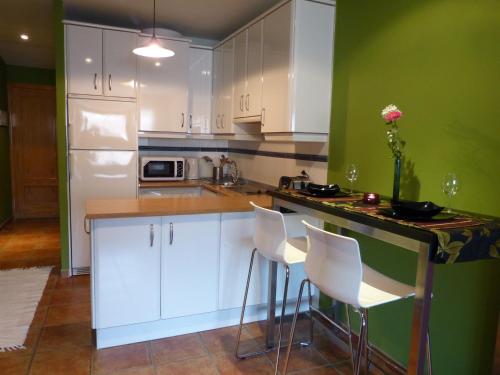 uma cozinha com armários brancos e uma parede verde em Casco Viejo Candeleda em Candeleda