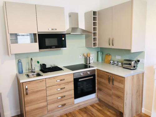 a kitchen with white cabinets and a stove top oven at Flat 12A - Central, modern, bright apartment with free wifi in Oban