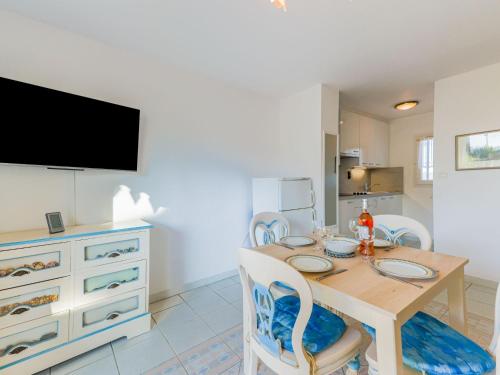 d'une salle à manger avec une table, des chaises et une télévision. dans l'établissement Holiday Home La Belle Créole by Interhome, au Cap d'Agde