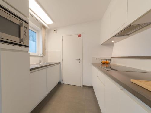 eine weiße Küche mit einer Spüle und einer Mikrowelle in der Unterkunft Apartment Ocean by Interhome in Bredene