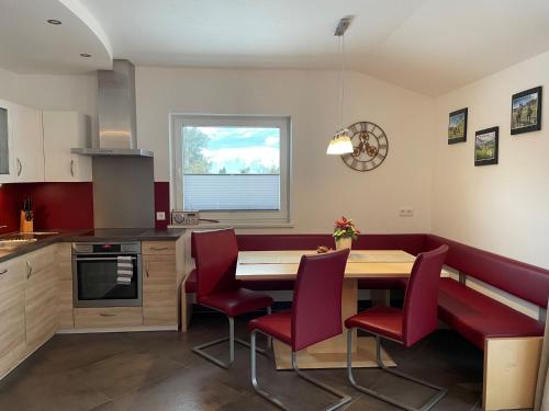 uma cozinha com uma mesa de madeira e cadeiras vermelhas em Apartment Fankhauser by Interhome em Piesendorf