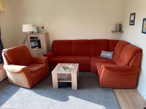 a living room with a red couch and a coffee table at Holiday Home Kiel by Interhome in Norddeich