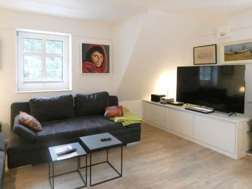 ein Wohnzimmer mit einem schwarzen Sofa und einem Flachbild-TV in der Unterkunft Holiday Home Grenzenlos by Interhome in Bad Brambach
