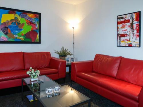 a waiting room with two red couches and a table at Apartment Am Sternberg 250 by Interhome in Frankenau