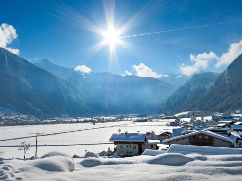 a village covered in snow with the sun in the sky at Apartment Neuner by Interhome in Hippach