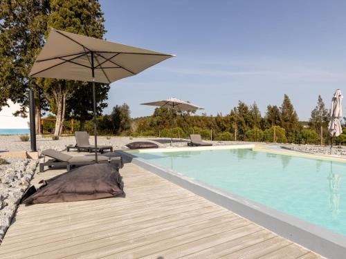 a swimming pool with an umbrella and chairs and a table at Holiday Home Quinta de Santa Emilia 2 by Interhome in São Martinho