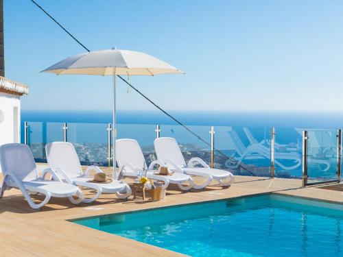 een zwembad met witte stoelen en een parasol bij Holiday Home Mediterraneo by Interhome in Almuñécar