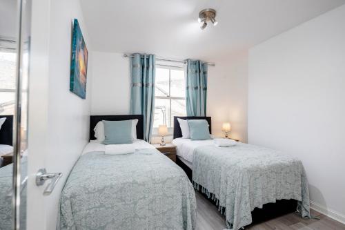 two beds in a white room with blue curtains at Beautiful 1-Bed Apartment in London Lewisham in London