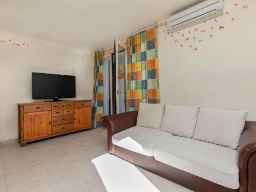 ein Wohnzimmer mit einem Sofa und einem TV in der Unterkunft Apartment Mitsu by Interhome in Tossa de Mar