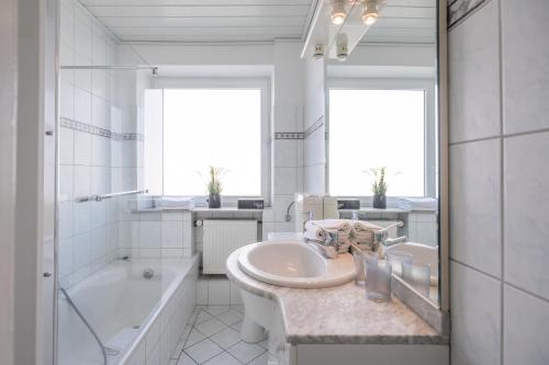 Un baño blanco con lavabo, bañera y un tubo. en Onkel Theodor, en Husum